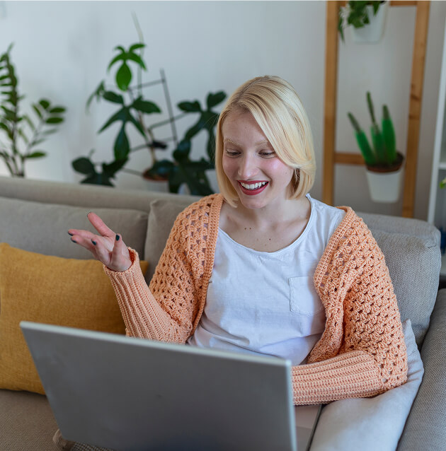 Smiling woman on a couch talking during a video visit on her laptop