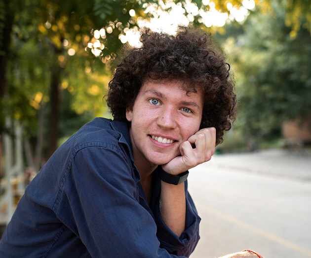 Young man with curly hair smiling outdoors