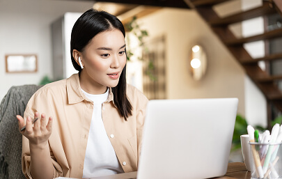 Woman with earbuds talking during a video call on her laptop