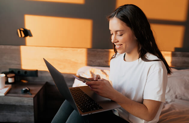 Woman at a desk reviewing her laptop in warm evening light