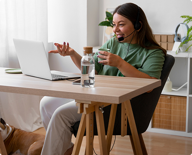 Clinician wearing a headset gesturing during a video appointment at her laptop