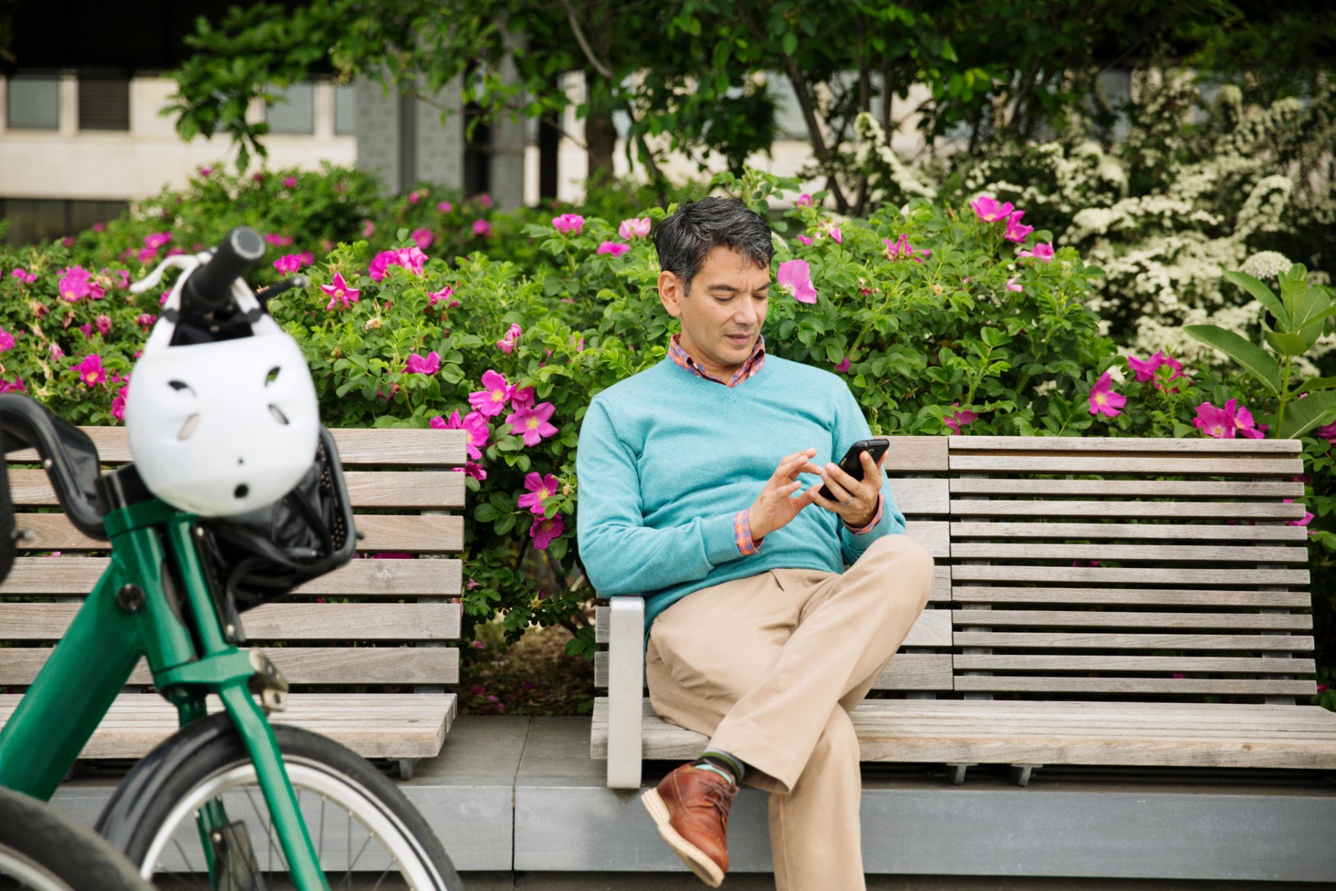 Man using his phone on a park bench