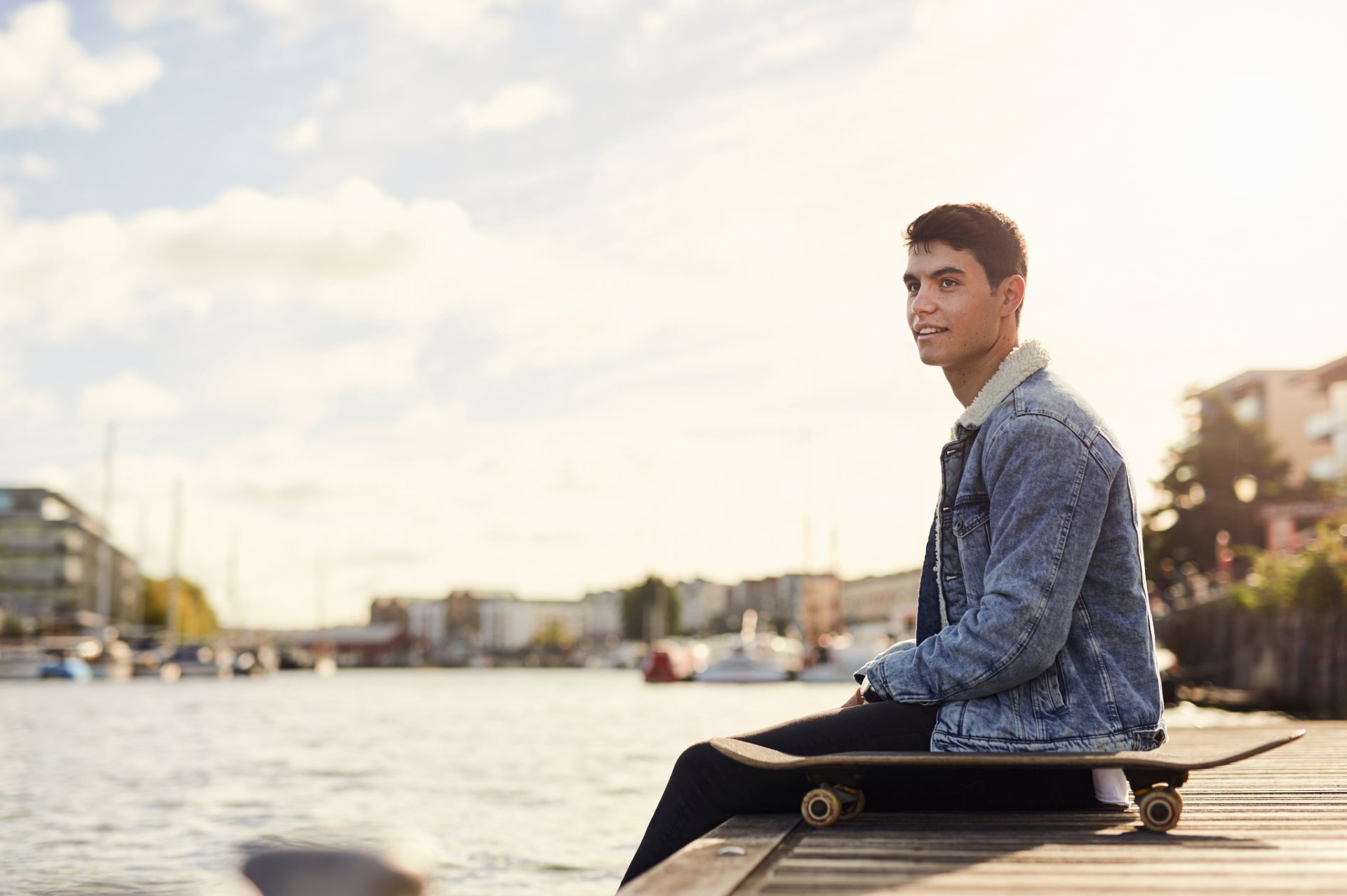 Young man sitting on a dock by the water
