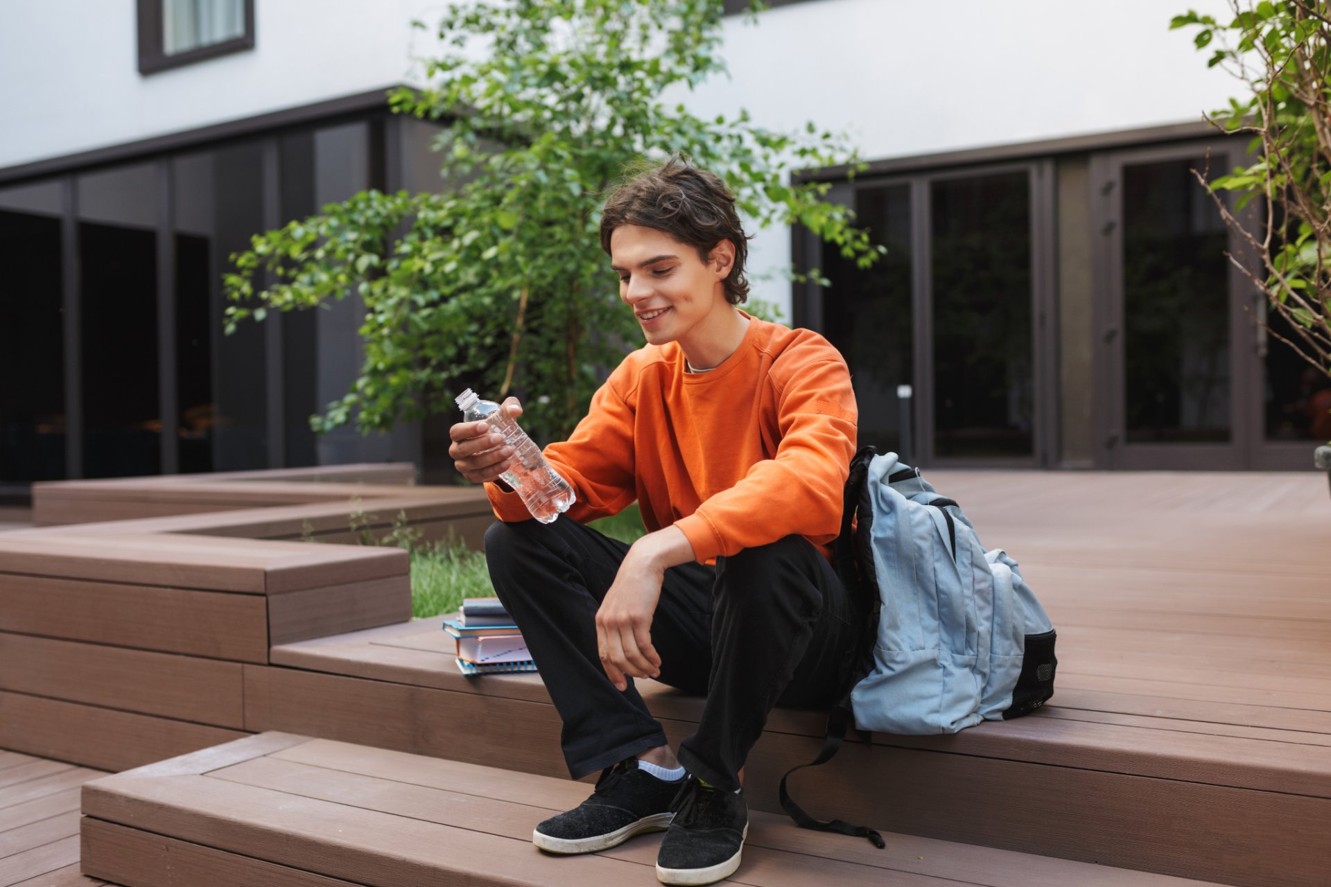 Young man sitting on outdoor steps holding a water bottle